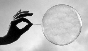 A person popping a bubble with a needle